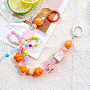 Close-up of candy-colored beaded phone strap with alphabet beads on decorative background