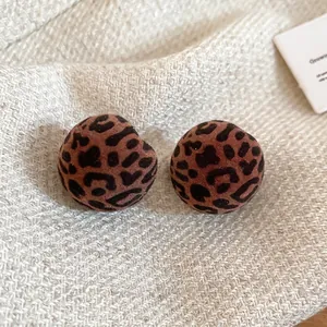Flocked red leopard print round stud earrings on a warm knit background for winter