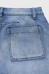 Détail de la taille d'un jean bleu avec poche arrière et texture en sergé