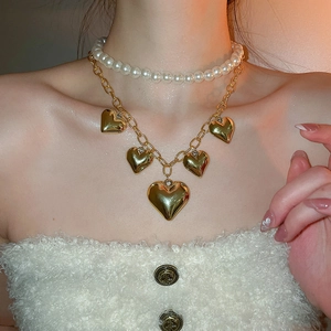 Close-up of vintage double-layer necklace with gold hearts and white faux pearls