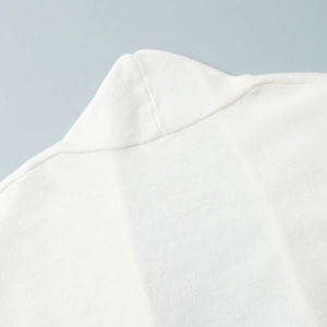 Detail of white knit cardigan showing high-neck structure and fine textured stitching