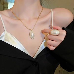Détails du collier et de la bague plaqués or avec d'élégantes perles ovales sur un modèle