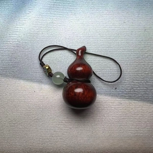 Detail of sandalwood gourd keychain with green jade bead and golden metal ornament