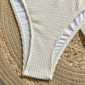 Detail of white textured seersucker fabric swimwear on a woven straw mat