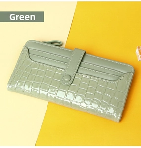 Detail view of long green women's wallet with crocodile embossed pattern and card slots