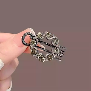Macro shot of a gunmetal hair claw clip featuring large grey crystals and white rhinestones