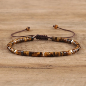 Handmade woven imperial stone bracelet with tiger eye beads and adjustable cord on wood