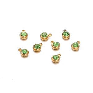 Vue macro de huit pendentifs dorés avec pierres en zircon vert pour création de bijoux