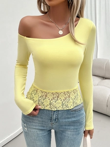Detail of yellow one-shoulder long sleeve top featuring intricate lace hem and slim fit