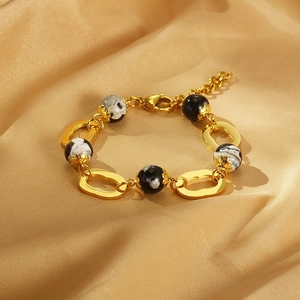 Détail d'un bracelet en titane plaqué or 18 carats avec perles en résine sur soie champagne