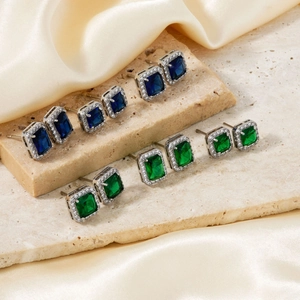 Elegant square stud earrings with blue and green gemstones on refined silk background