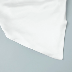 Détail du tissu blanc à texture soyeuse montrant la surface lisse et la coupe précise