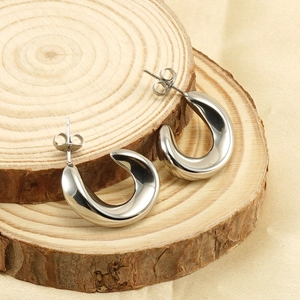 Close-up of polished silver U-shaped stainless steel earrings on a natural wood block