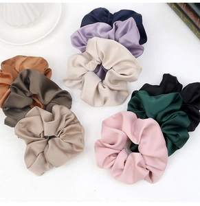 Flat lay of colorful oversized satin scrunchies in pink, green, white, and brown shades