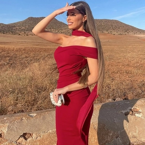 Détail de la robe moulante rouge avec lien au cou et sac à main blanc clouté
