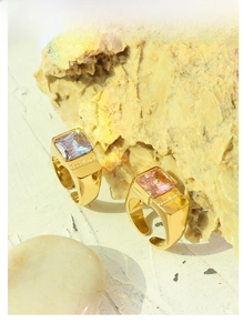 Close-up of gold geometric titanium rings with purple and pink zircon stones on stone