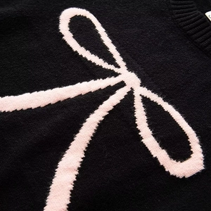 Close-up of black knit sweater showing fuzzy texture and pink jacquard bow detail