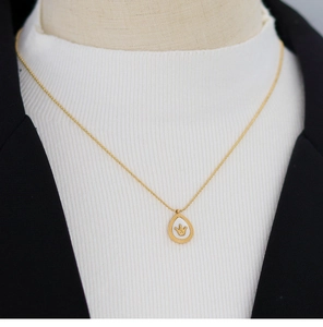 Detailed view of crown pendant with white mother of pearl on a gold chain necklace