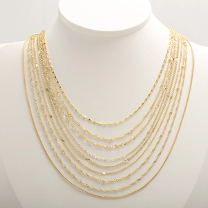 Layered gold stainless steel necklaces with snake, link and rope chain styles on model