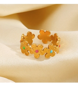 Gros plan sur la bague fleur dorée ajustable avec émail coloré sur un fond de soie