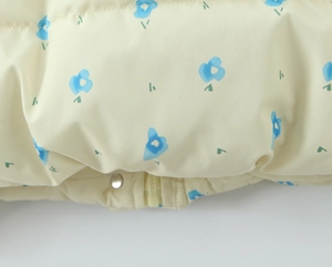 Detailed view of elastic hem and floral pattern on a yellow hooded cotton-padded jacket