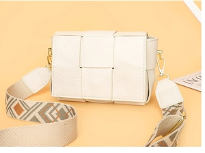 Detail of cream woven leather bag featuring a wide geometric embroidered shoulder strap