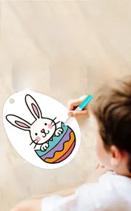 Close-up of children coloring Easter DIY cards with a blue marker on a wooden table