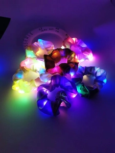Close-up of vibrant LED glowing scrunchies in multiple colors on a ceramic tray