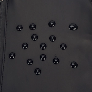 Waterproof detail of a black crossbody chest bag with hydrophobic droplets on fabric
