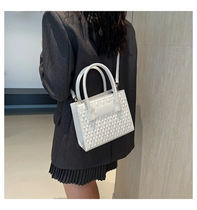 Vue détaillée du sac à bandoulière blanc gaufré porté par un mannequin en veste noire