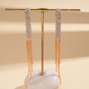 Close-up of gold tassel earrings with rhinestone mesh on a minimalist jewelry stand