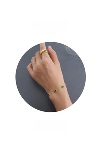 Dettaglio del bracciale a catena dorata con zirconi rettangolari verde smeraldo