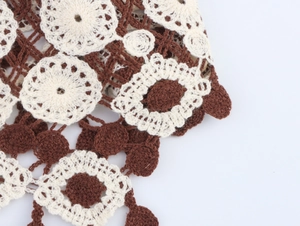 Macro view of brown and cream crochet knit pattern with hollow floral and geometric details