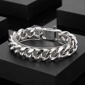 Detailed view of silver stainless steel Cuban link bracelet with secure clasp on black podium