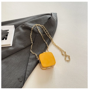 Flat lay of a yellow mini chain square bag on a grey blazer for a modern fashion look