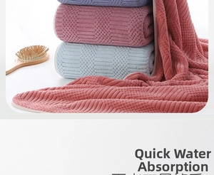 Detail of coral fleece bath towel set showing waffle weave texture and binding edges