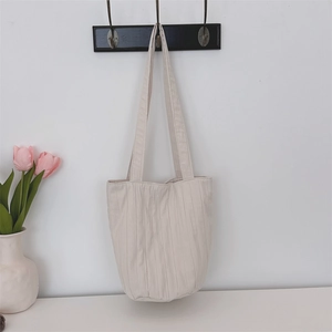 Primer plano del bolso tote de lona plisada crema con rayas verticales de moda