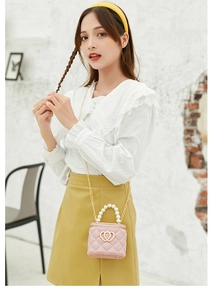 Pink quilted mini bag featuring pearl handle, gold chain strap, and double heart clasp