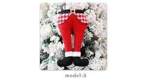 Detail of Christmas elf legs decoration with red pants and black boots on a snowy tree