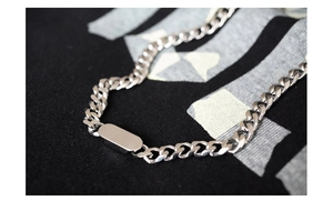 Macro detail of silver titanium steel Cuban chain bracelet with smooth rectangular ID tag