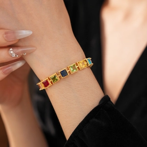 Gros plan d'un bracelet vintage doré avec des pierres de zircone carrées multicolores