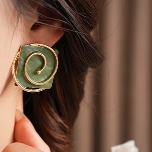Macro detail of vintage green square earrings with golden spiral on model's ear