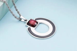 Detail of silver titanium pendant featuring a red square gemstone and black circular ring