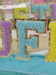 Close-up of chenille letter patches with glitter edges on a waterproof makeup bag