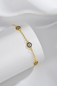 Macro shot of gold Evil Eye bracelet with blue and white crystals on white fabric