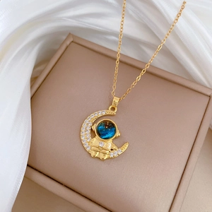 Detail of gold astronaut necklace with sparkling moon pendant and blue planet helmet