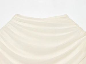 Detailed close-up of layered cream mesh fabric with pleated texture on the dress