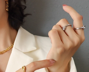 Close-up of model wearing gold U-link chain necklace with knotted mixed-metal rings