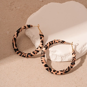 Detail shot of leopard print faux leather hoop earrings on white stone display