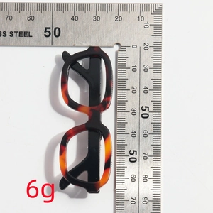 Detail view of acetate tortoiseshell glasses brooch on scale showing 6g weight
